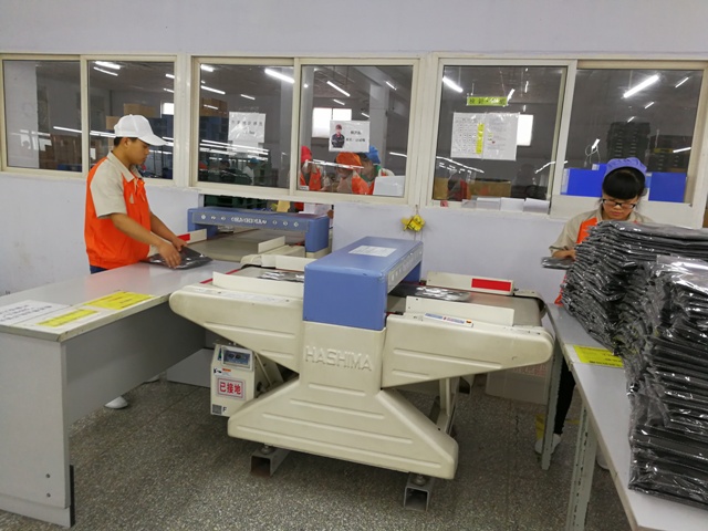 荣岛成衣检品车间，检品员逐件检查服装外观与缝制质量